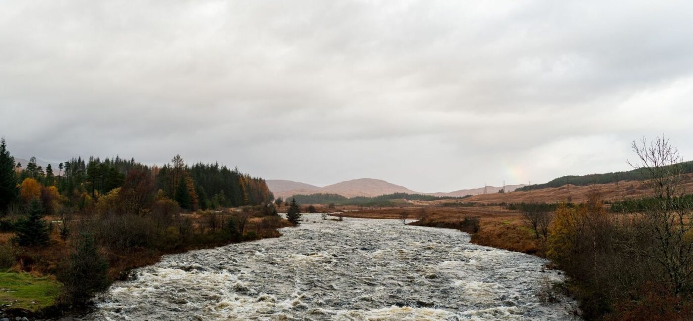 Fast, turbid river flowing through an autumn Highland landscape